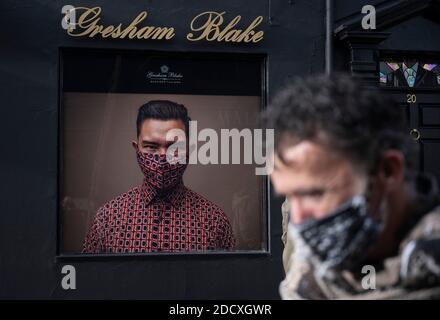 Brighton UK 23. November 2020 - EIN Mann im Gesicht bedeckt passiert das bekannte Gresham Blake Designer-Modegeschäft in der trendigen North Laine-Gegend von Brighton, die im Moment während der Lockdown zwei Einschränkungen in England geschlossen ist. Die Regierung wird erwartet, dass nicht wesentliche Geschäfte in der nächsten Woche zu öffnen, wenn sie die Beschränkungen in England zu erleichtern : Credit Simon Dack / Alamy Live News Stockfoto