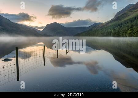 Neblige Reflexionen an einem frühen Herbstmorgen in Buttermere im englischen Lake District. Stockfoto