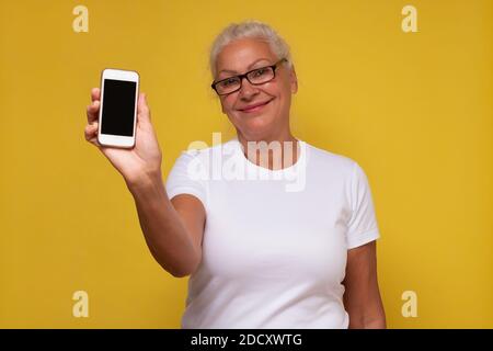 Ältere kaukasische Frau zeigt leeren Smartphone-Bildschirm Stockfoto