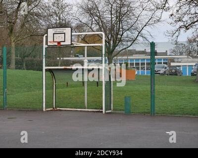 Orange Basketball Reifen weiß Metall Ziel Beiträge kombiniert hart spielen Oberfläche mit hohen grünen Einzäunung umgeben Gras hinter Stockfoto