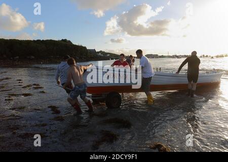 Die Crew von St. Mary’s Gig zieht das Boot nach dem Rennen an Land. Isles of Scilly, Cornwall, Großbritannien. Stockfoto