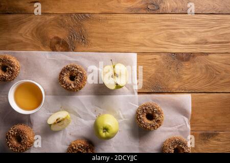 Gebackene Apfelmost-Donuts mit Apfelfrüchten und Apfelwein auf Backblechen auf natürlichem Holztisch. Bereit, Snack zu essen. Kleine Partie hausgemachtes Essen. Direc Stockfoto