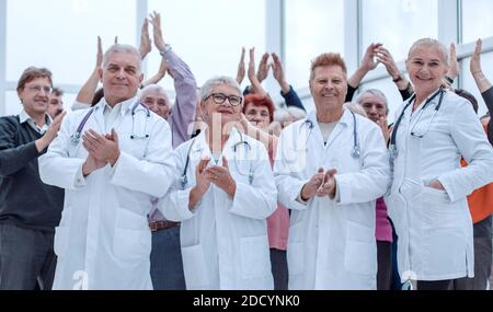 Ärzte und eine Gruppe reifer Menschen applaudieren Stockfoto