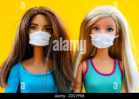 Tambow, Russische Föderation - 12. Juni 2020 zwei Barbie Puppen mit medizinischen Masken. Gelber Hintergrund. Stockfoto