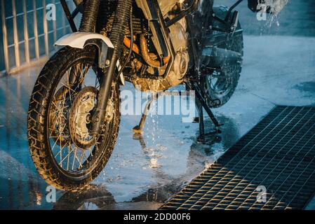 Waschserie für Motorräder. Ein Motorrad bei einer Autowäsche bei Sonnenuntergang waschen. Stockfoto
