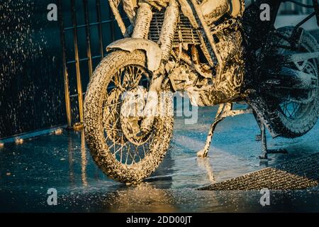 Waschserie für Motorräder. Ein Motorrad bei einer Autowäsche bei Sonnenuntergang waschen. Stockfoto