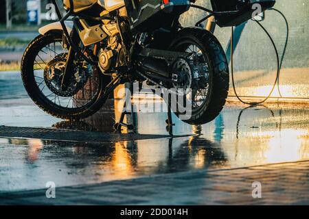 Waschserie für Motorräder. Ein Motorrad bei einer Autowäsche bei Sonnenuntergang waschen. Stockfoto