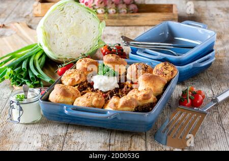 Irischer Schuster mit Scones. Hackfleisch aus Schweinefleisch und Rindfleisch mit Kohl, Tomaten und Käse in einer Kasserolle auf rustikalem Tisch gebacken Stockfoto