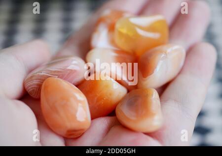 Carnelian in der Hand der Frau gestolpert. Hochwertige Karneol-Steine. Kraftvolle Heilung Kristall reiki. Hochwertige schöne gebänderte Karneol, üppige ora Stockfoto