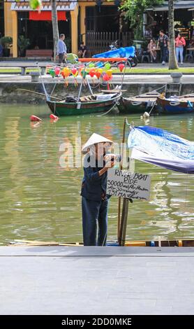 Eine alte vietnamesische Frau mit einem traditionellen konischen Hut auf einem Boot zur Miete auf dem Thu Bon River, Hoi an, Vietnam, Asien Stockfoto