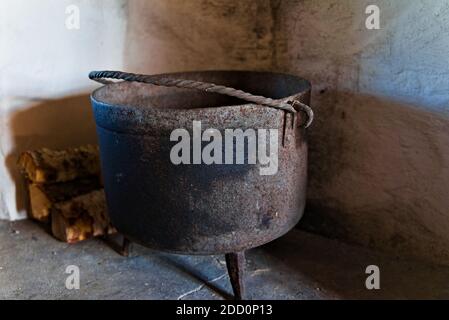 Mittelalterlicher schwarzer gusseiserner Topf am Kamin. Stockfoto