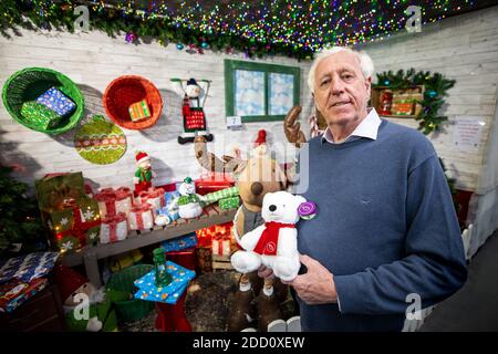 Robin Mercer vom Hillmount Garden Centre in Belfast, der den Hillmount Christmas Bear namens Ava in der Santa's Grotto hält. Stockfoto