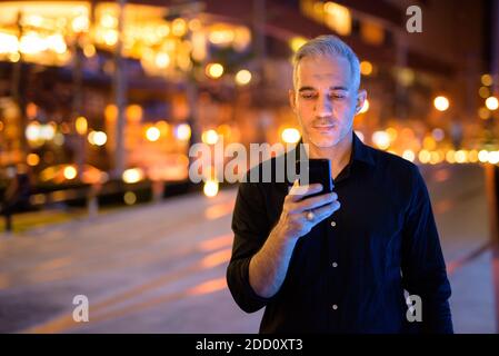 Attraktiver Mann in der Nacht auf der Straße mit Handy Stockfoto