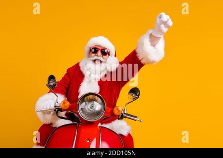 Portrait von seinem er nett lustig fröhlich fröhlichen Santa Reiten Moped schnelle Fahrt mit Spaß steigende Hand nach oben tragen Flauschiges Kostüm isoliert hell Stockfoto