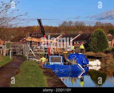 Ein neuer hölzerner Schleusenbalken wird von einem Arbeitsboot als Teil der neuen Kopftore am Canal and River Trust an der Schleuse Ell Meadow bei Wigan angehoben. Stockfoto