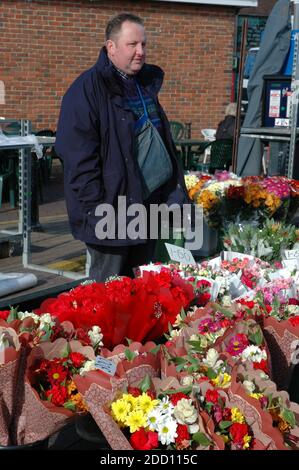 Mann, der hinter seinem Blumenstand auf dem Chichester Markt steht. Februar. West Sussex, England. Modellversion Stockfoto