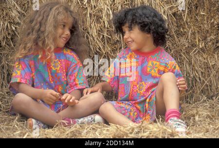 Zwei kleine Schwestern sitzen auf Heuballen und plaudern Stockfoto