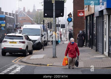 Während die zweite nationale Sperre mit etwas mehr als einer Woche vor dem Beginn des neuen Tier-Systems fortgesetzt wird, kommen Menschen, von denen viele Gesichtsmasken tragen, in die Kings Heath High Street, da alle nicht wichtigen Geschäfte geschlossen sind, während einige am 23. November 2020 in Birmingham, Großbritannien, Handel treiben. Die neue nationale Lockdown ist ein großer Schlag für die Wirtschaft und für einzelne Unternehmen, die bereits mit nur begrenzten Dienstleistungen zu kämpfen hatten. Stockfoto