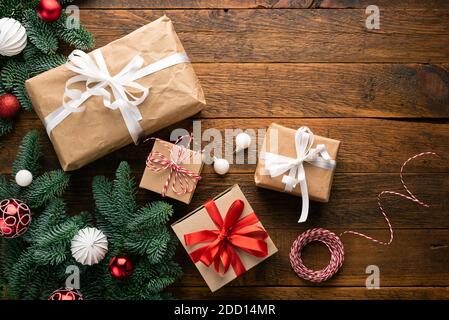 Weihnachten oder Neujahr Hintergrund mit Geschenken in Bastelpapier auf Holzhintergrund bedeckt. Kopieplatz für Text oder Design in der Draufsicht Stockfoto
