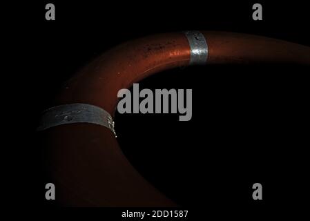 Orange round life buoy with reflectors isolated on black background. Stockfoto