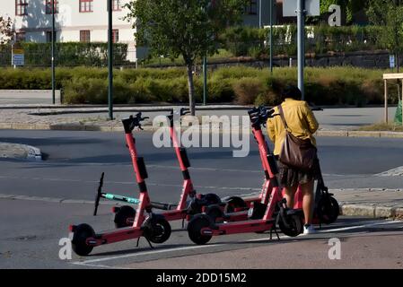 Oslo, Norwegen - 29. August 2020: Frau, die sich ein Elektro-Kick-Fahrrad von der Mietstation in der Stadt ausleihen. Stockfoto