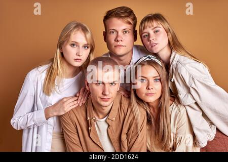 Portrait von trendy stilvolle Jugend posiert bei der Kamera isoliert auf braunem Hintergrund, gutaussehende männliche und schöne Frauen in modischen braunen Kleidung stehen zusammen, Modelle Stockfoto