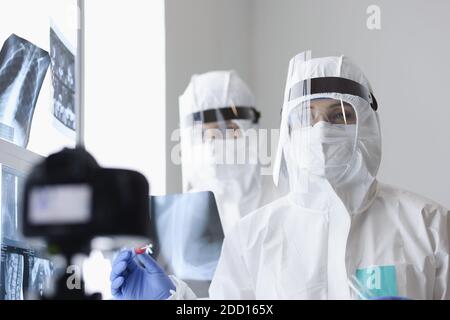 Ärzte in Schutzschirmen und Anti-Pest-Anzüge Blick in die Kamera Im Röntgenraum Stockfoto