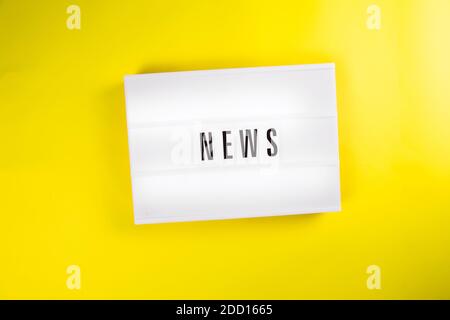 Nachrichtenwort auf Leuchtkasten auf gelbem Hintergrund isoliert Draufsicht, flach liegend Stockfoto