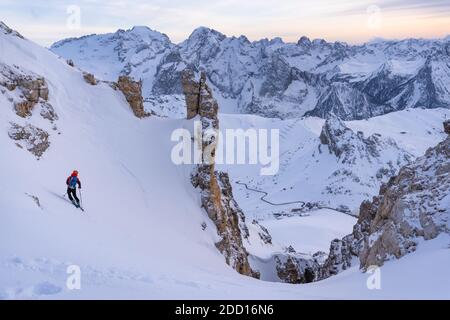 Skifahrer, die in Joel Couloir mit dem Sonnenuntergang und Marmolada Range vor sich abfallen. Sass Pordoi, Dolomitas Stockfoto