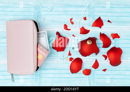 Flaches Lay mit medizinischer Maske, zerbrochener weihnachtskugel, Geldbörse, Kreditkarte und Geld. Stockfoto