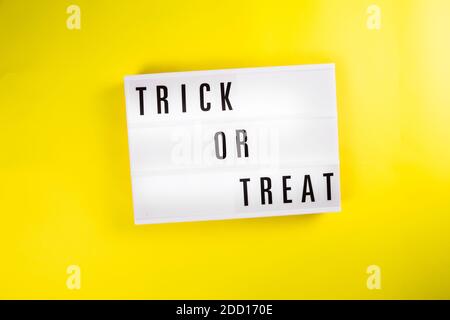 Trick or Treat Meldung auf Leuchtkasten auf gelbem Hintergrund isoliert Stockfoto