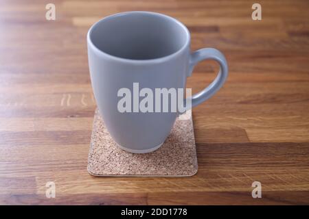 Grauer Becher, der zu Hause auf einem Holztisch steht Nahaufnahme Stockfoto