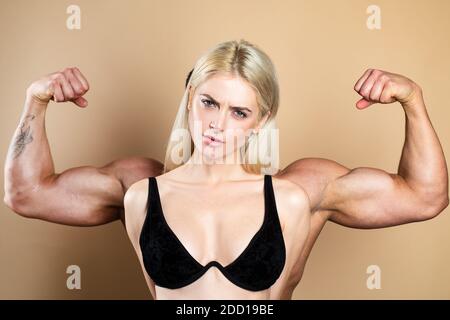 Lustiges Fitness-Paar. Funky Mädchen haben Bodybuilding Praxis, zeigen Bizeps. Eine junge weibliche Modell posiert mit männlichen großen Muskeln. Spaß an Fitness. Frauenmacht Stockfoto