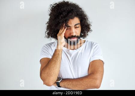 Trauriger arabischer Mann hat Probleme, er ist deprimiert, hält Hand am Kopf, steht in Gedanken, isoliert auf weißem Hintergrund Stockfoto