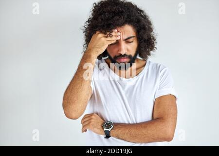 Junger arabischer inder mit langen Haaren hat Kopfschmerzen, er leidet an Migräne, er hat einen Migräne-Angriff. Isolierter weißer Hintergrund Stockfoto