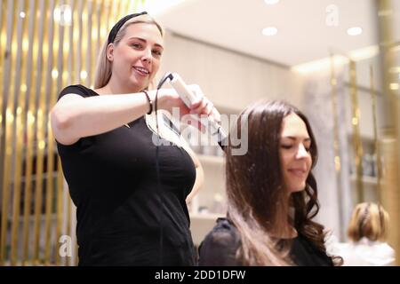 Haarschneider macht Locken für Frau Stockfoto