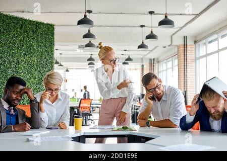 Unhöflich wütend weibliche Chef Executive ist unzufrieden irritiert von Mitarbeitern, schreien sie an, inkompetente Arbeitnehmer. In modernen Büro Stockfoto