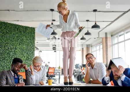 Unhöflich wütend weibliche Chef Executive ist unzufrieden irritiert von Mitarbeitern, schreien sie an, inkompetente Arbeitnehmer. In modernen Büro Stockfoto