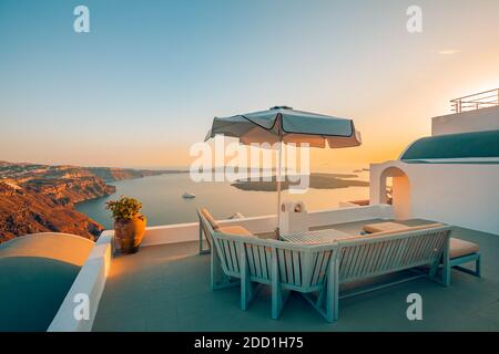 Terrasse bei Sonnenuntergang auf Santorini, Griechenland. Wunderschönes Resort Caldera Blick Sonnenuntergang Himmel. Entspannung, Sonnenschirm und Stühle, Tisch. Sommerurlaub Stockfoto