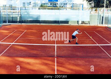 Mann spielt Tennis auf dem Sandtennisplatz Blick aus der Ferne Stockfoto