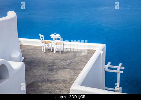 Minimalistische Reiselandschaft mit Stühlen und weißer Architektur in Santorini. Luxusurlaub im Sommer, Urlaub für Paare. Meerblick, romantische Stimmung, entspannen Stockfoto