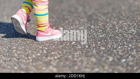 04.12.19 - Provence, Frankreich: Süße kleine Mädchenbeine mit Nike rosa Sportschuhen und Regenbogenhosen. Niedliche Foto im Freien von Mädchen spielen. Stockfoto