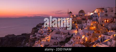 Atemberaubende Sonnenuntergangslandschaft. Schöne Aussicht auf fabelhafte Dorf Oia mit traditionellen weißen Häusern und Windmühlen in Santorini Insel bei Nacht, Griechenland Stockfoto