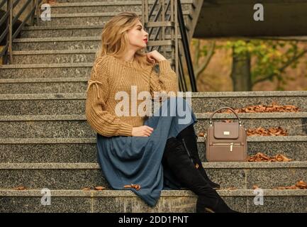 Echte Entspannung. Mädchen lange blonde Haartreppen. Legere Studenten. Herbstsaison. Weibliche Schönheit. Modelart: Mädchen in Wellrock und Pullover. Plissierter Trend: Herbstfrau lockiges Haar im Freien. Stockfoto