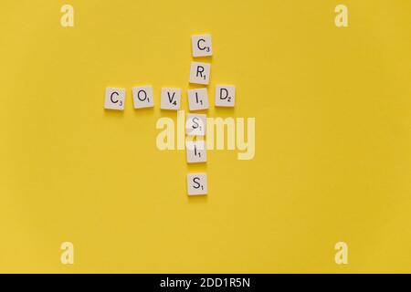 Covid-Krise. Wort Kreuzworträtsel Scrabble Spiel auf einem gelben Hintergrund. Speicherplatz kopieren. Stockfoto