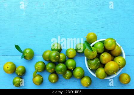 Gelbgrüne Calamansi, Calamondin oder philippinische Limette tropisches Fruchtmuster in hellblauem Holzhintergrund. Asiatische Sommer Zitrusfrüchte flach legen. Stockfoto