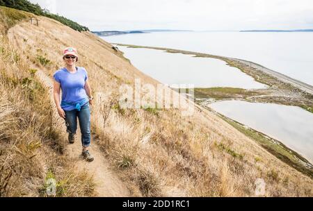 Eine Frau, die auf Ebey's Landing Bluff Trail, Whidbey Island, Washington, USA, läuft. Stockfoto