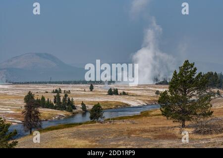 Der Firehole River fließt durch das Midway Geyser Basin, Yellowstone National Park, Wyoming. Dampf steigt aus dem Excelsior Geysir. Stockfoto