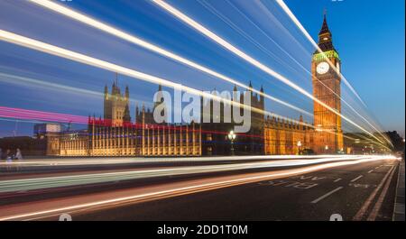 Autos fahren in der Dämmerung entlang der Westminster Bridge, Big Ben und den Houses of Parliament in London, England. Stockfoto