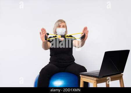 Ältere Frau trägt Maske hält Widerstand Band zeigt Stopp Coronavirus. Stockfoto